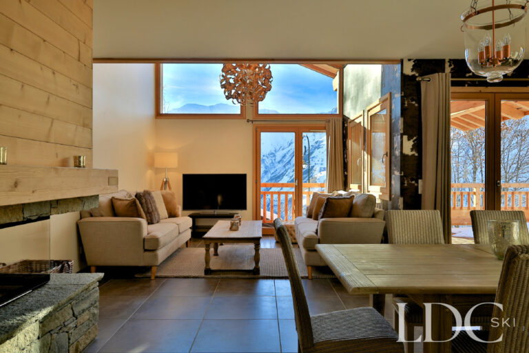 Open-plan dining and living area with fireplace and mountain views at Chalet Aphylla