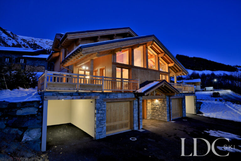 Chalet Aphylla illuminated against the snowy mountains at dusk in St Martin de Belleville