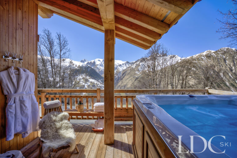 Outdoor hot tub beneath the covered terrace overlooking the mountains at Chalet Aphylla