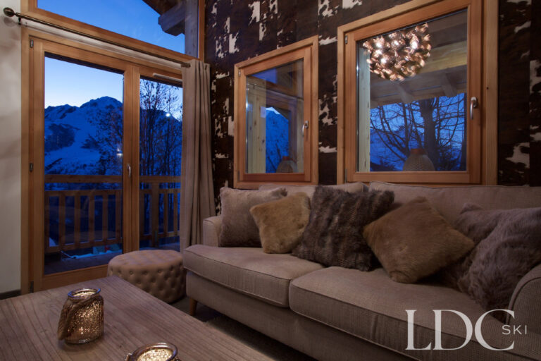 Cosy living area with mountain views through the windows at dusk at Chalet Aphylla