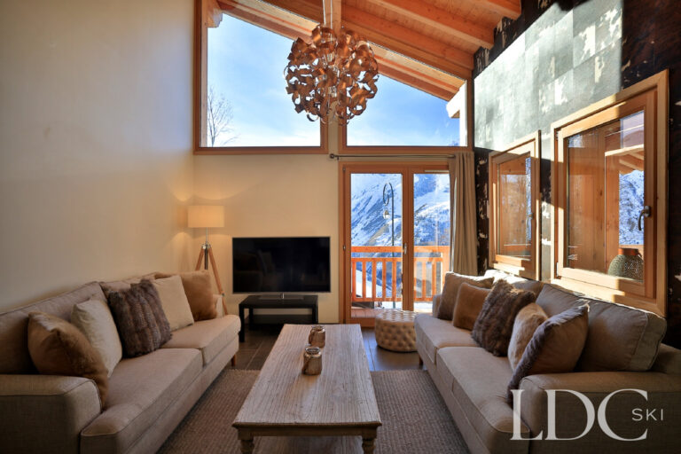 Double-height living room with fireplace and mountain views at Chalet Aphylla