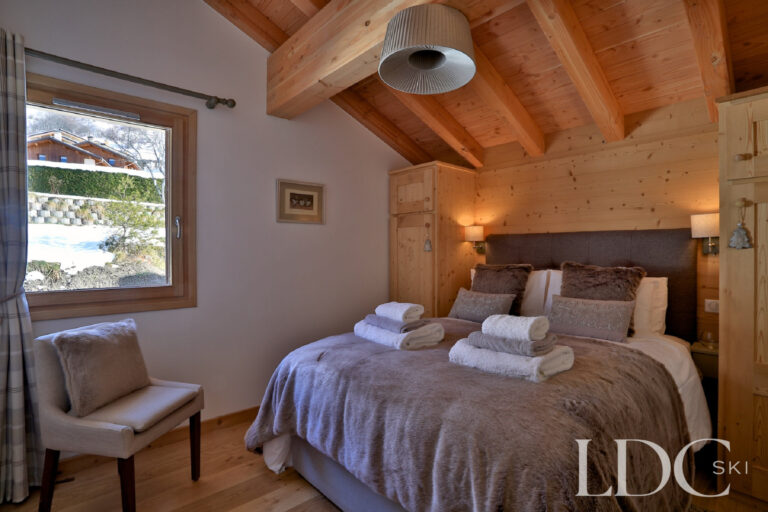 Double bedroom beneath a timber ceiling at Chalet Aralia