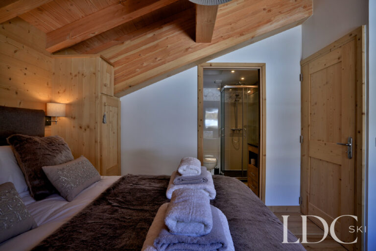 Bedroom with timber detailing and adjoining bathroom at Chalet Aralia
