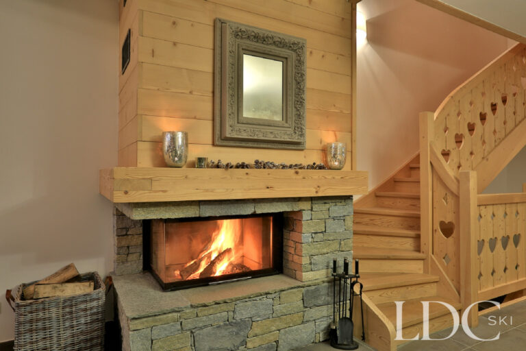Stone fireplace with log fire at Chalet Aralia
