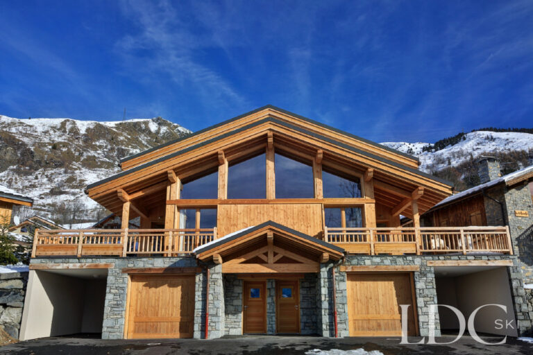 Front of the chalet building housing Chalet Aralia against the snowy mountains