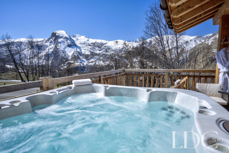 Private outdoor hot tub framed by panoramic mountain scenery at Chalet Aralia
