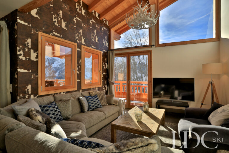Chalet Aralia's alpine living room with fireplace, large windows and mountain views
