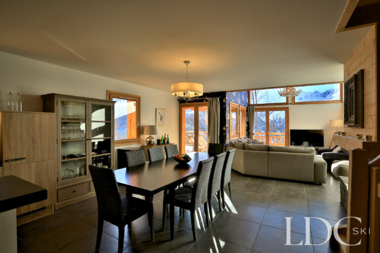 Open-plan living and dining area with large windows at Chalet Aralia