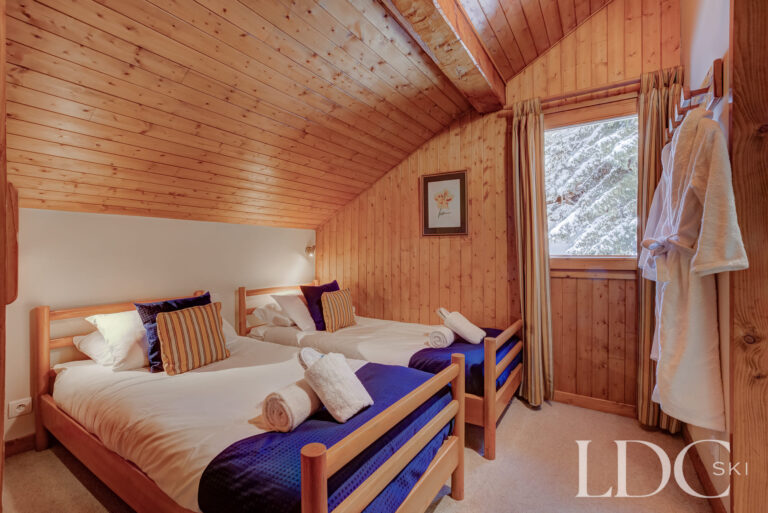 Twin bedroom with timber-panelled walls at Chalet Cecilia