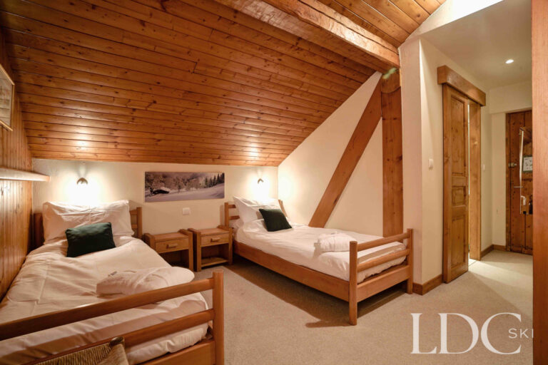Twin bedroom beneath a sloping timber ceiling at Chalet Cecilia