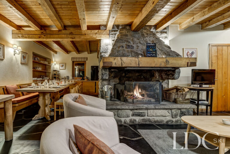 Open-plan lounge and dining area centred around the stone fireplace at Chalet Cecilia