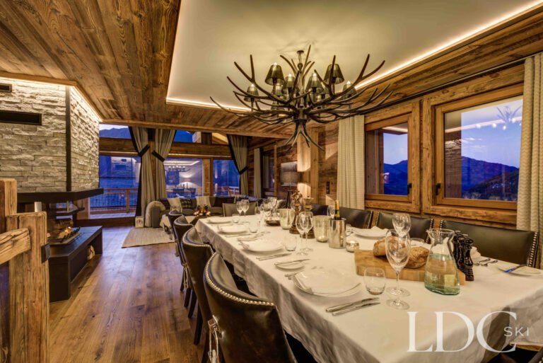 Dining table laid for dinner beneath statement lighting at Chalet Chez Bugi