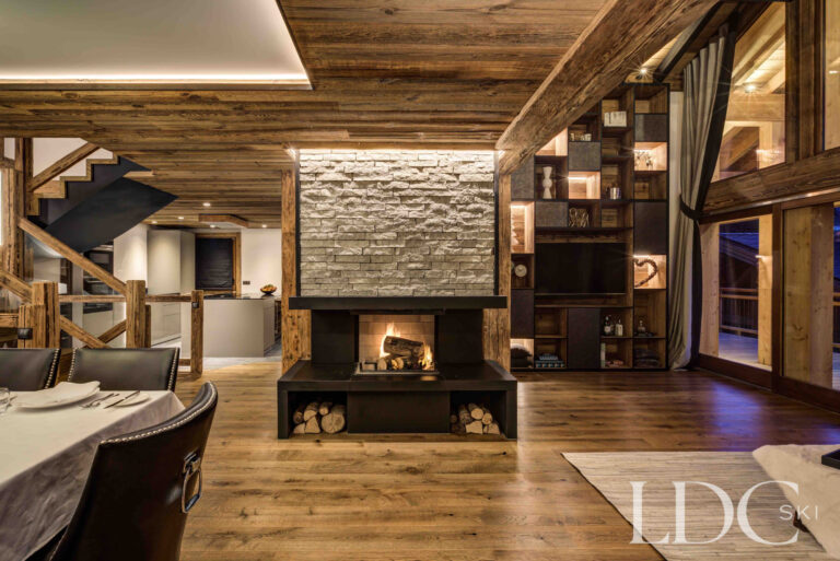 Stone fireplace and living area illuminated in the evening at Chalet Chez Bugi