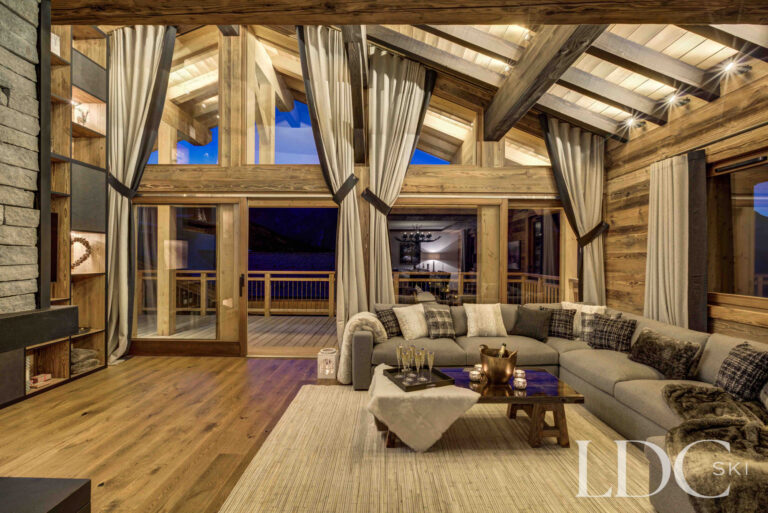 Double-height living room with mountain views at dusk at Chalet Chez Bugi
