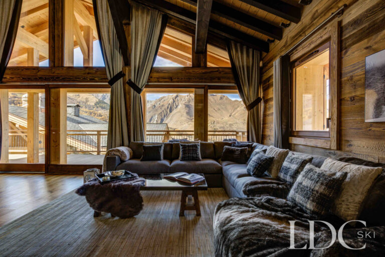 Double-height living room with floor-to-ceiling windows overlooking the mountains at Chalet Chez Bugi