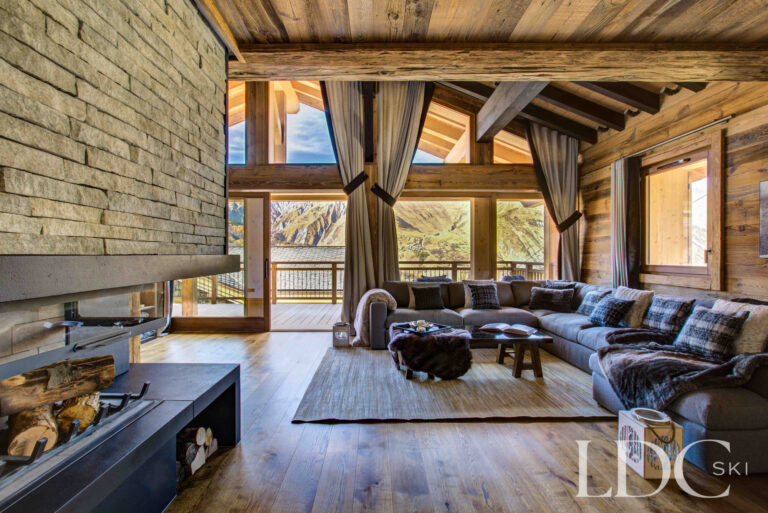 Chalet lounge looking past the stone fireplace towards the mountain-facing windows