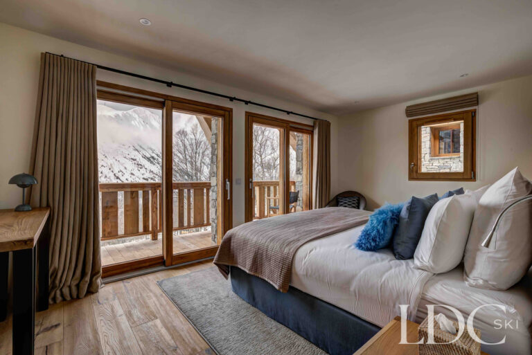 Bright double bedroom with balcony doors and snowy mountain views at Chalet Constantia