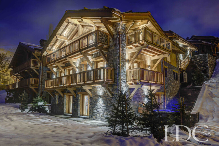 Chalet Constantia glowing warmly in the snow at night in St Martin de Belleville