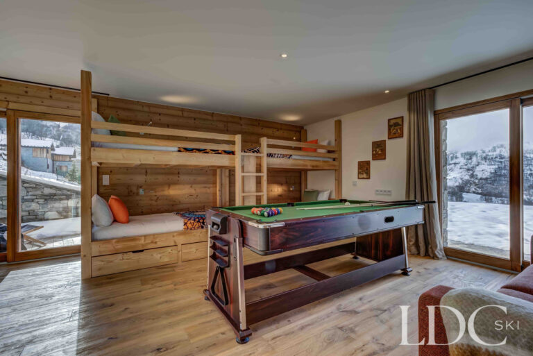 Pool table in the chalet's games room with snowy views outside