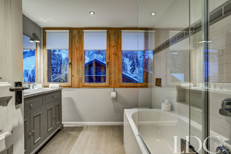 Bright en-suite bathroom with bath and separate shower at Chalet Pasarale