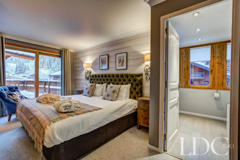 Double bedroom with adjoining en-suite bathroom and mountain views at Chalet Pasarale