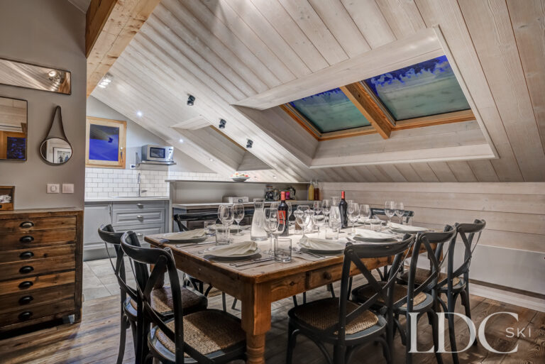 Chalet Pasarale dining room beneath a vaulted timber ceiling with roof windows