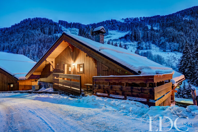 Chalet Pasarale illuminated at dusk in snowy Méribel