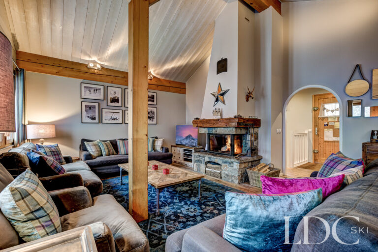 Spacious lounge with log fire, exposed beams and comfortable seating at Chalet Pasarale