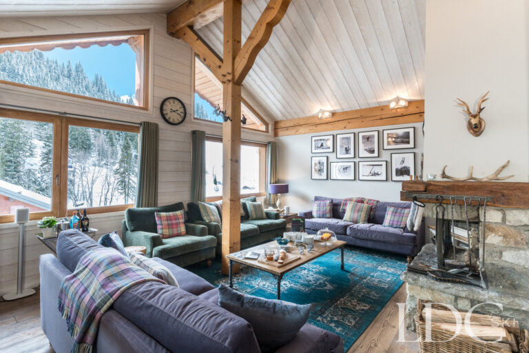 Comfortable lounge with large windows, mountain views and log fireplace at Chalet Pasarale