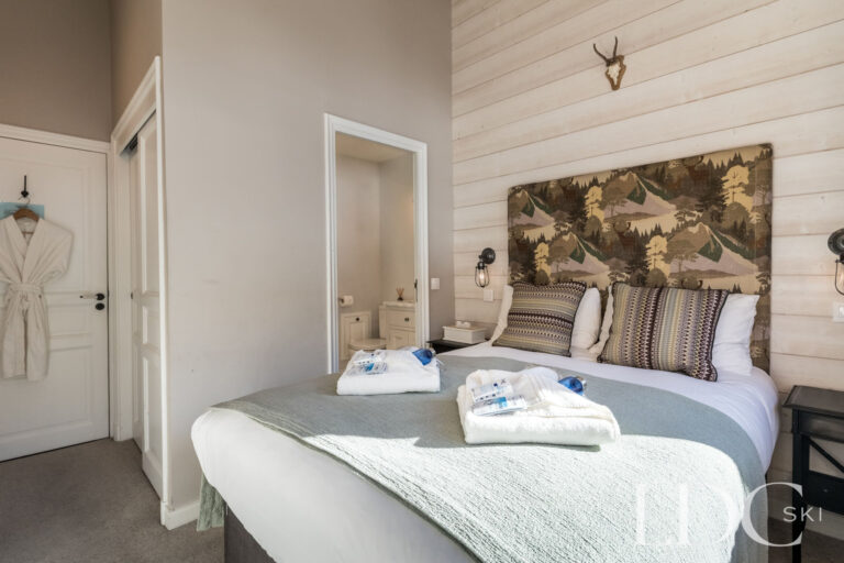 Double bedroom with Alpine artwork and en-suite bathroom at Chalet Quatre Meules
