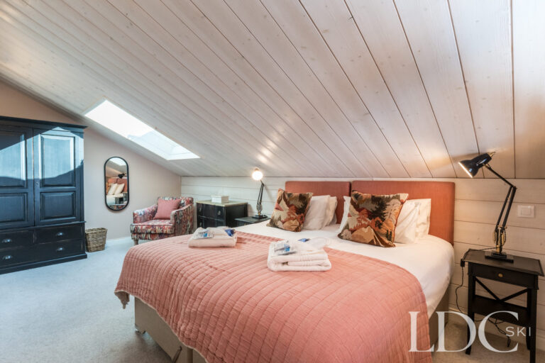 Double bedroom with soft Alpine-style furnishings at Chalet Quatre Meules