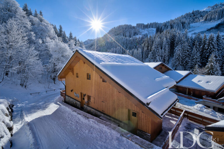 Snow-covered Chalet Quatre Meules beneath a blue winter sky in Méribel