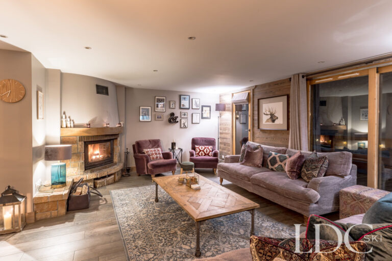 Comfortable lounge with log fire at night, comfortable seating at Chalet Quatre Meules