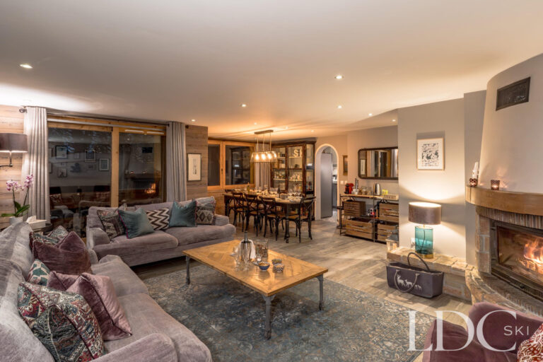 Spacious lounge with log fire, comfortable seating and dining area at Chalet Quatre Meules