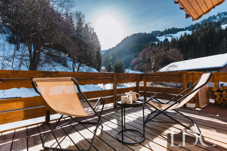 Sunny terrace set for afternoon tea with mountain views at Chalet Quatre Meules
