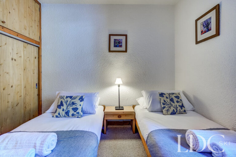 Twin bedroom with built-in wooden storage at Chalet Veronica in Méribel