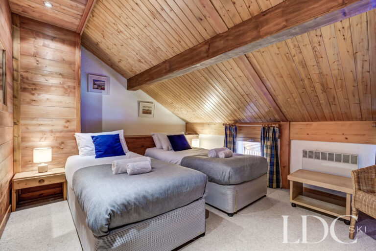 Twin bedroom beneath a traditional timber ceiling at Chalet Veronica