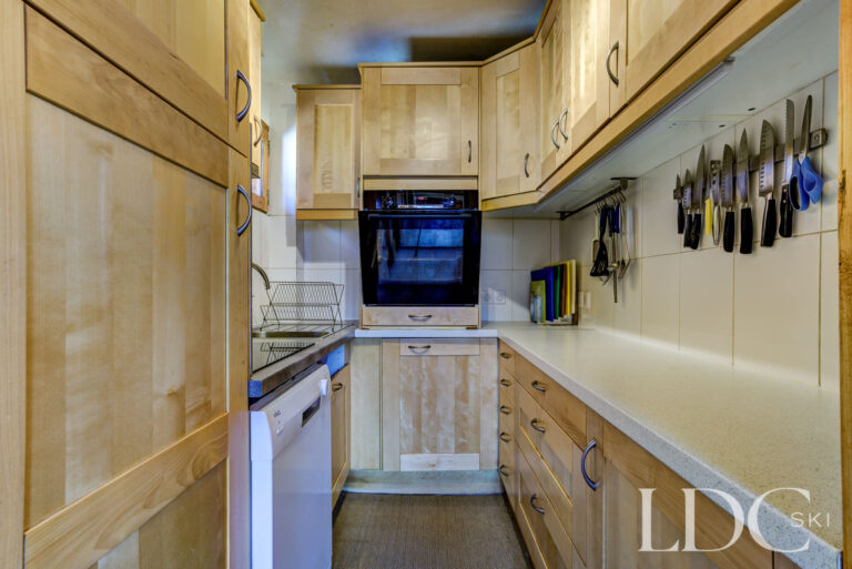 Compact fitted kitchen with timber cabinetry at Chalet Veronica in Méribel