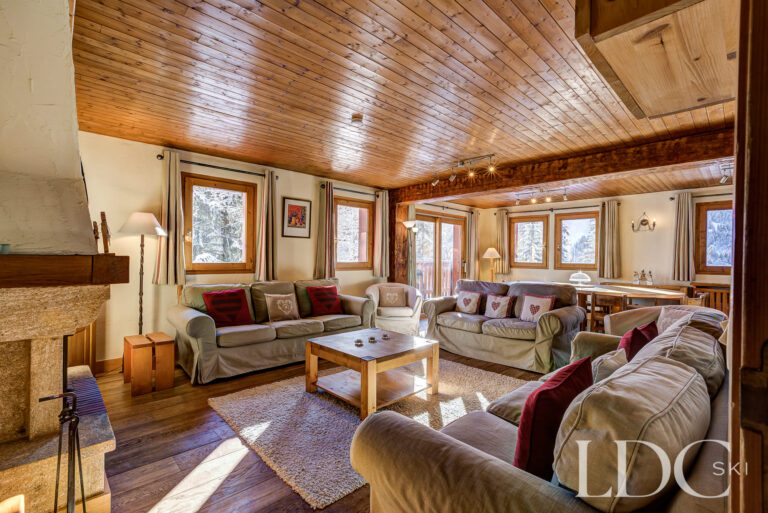 Comfortable chalet lounge with sofas, timber ceiling and fireplace at Chalet Veronica