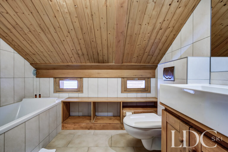Upstairs bathroom with bath beneath a timber-panelled ceiling at Chalet Veronica