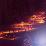 Torchlight ski descent illuminating the snowy slopes of Courchevel 1850 at night. © David André