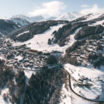 Aerial winter view of Courchevel Village surrounded by snowy slopes and forest. © Un Duo.