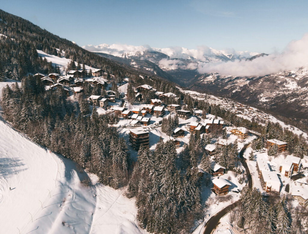 Courchevel Village surrounded by snowy mountains and forest in winter. © Un Duo.