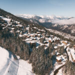 Courchevel Village surrounded by snowy mountains and forest in winter. © Un Duo.