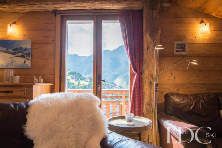 Cosy lounge at Encombres Tête de Fer with doors opening onto the balcony and mountain views in St Martin de Belleville