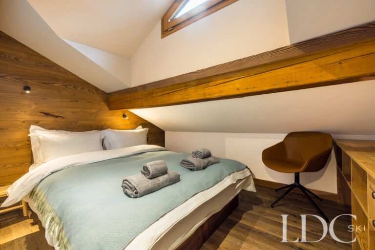 Blue bedroom arranged as a double beneath exposed timber beams at La Florette