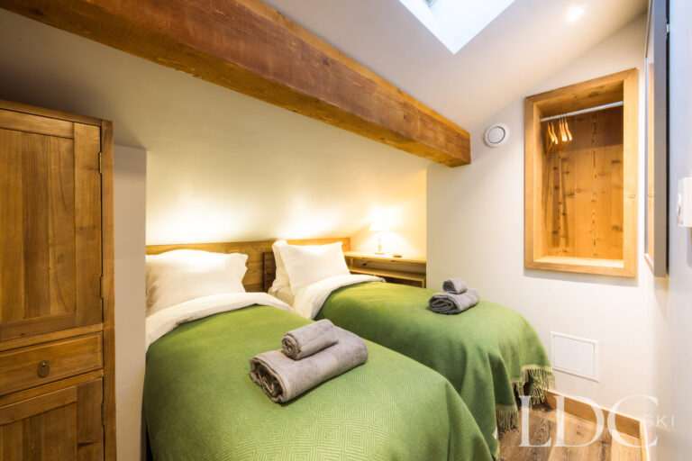 Green double bedroom with traditional timber detailing at La Florette