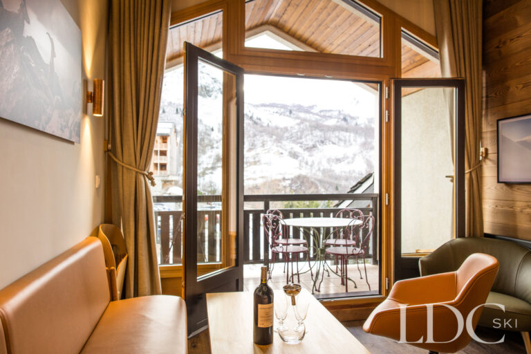 Lounge opening onto the balcony with snowy mountain views at La Florette in St Martin de Belleville