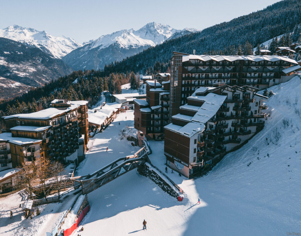 Aerial winter view of La Tania village surrounded by forest and ski slopes. © Un Duo.