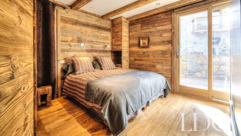 Double bedroom with balcony doors and snowy mountain views at Le Chalet
